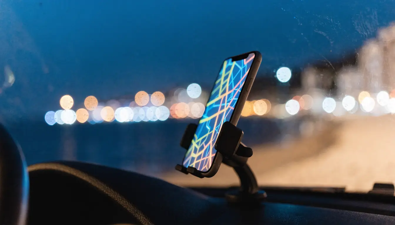 A rideshare driver's phone glowing in a dash mount at night in Oceanside — the app status that decides insurance coverage