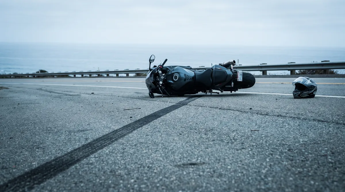 A motorcycle on its side with a helmet nearby after a crash on a coastal Oceanside highway